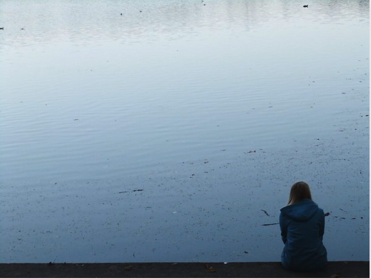 Picture of a woman looking out on a body of water alone
